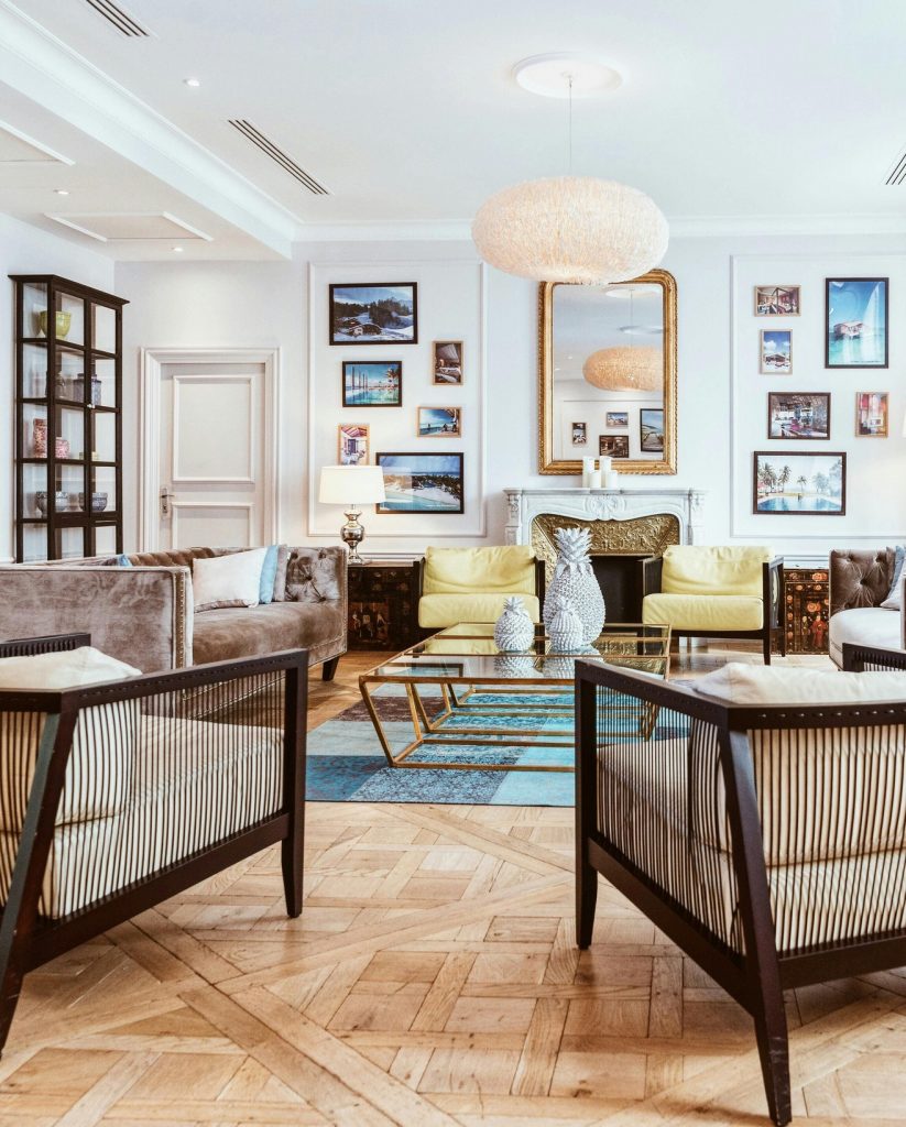 chetoi rénovation toulouse salon avec décoration plutôt maximaliste, avec plein de cadres accrochés au mur, une table basse centrale en verre et doré, entourée de canapé en velours et divers fauteuils.