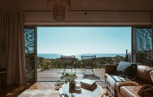 chetoi renovation toulouse, salon chaleureux qui donne sur une grande terrasse ouverte avec vue sur la mer ou l'océan et la nature, arbres.