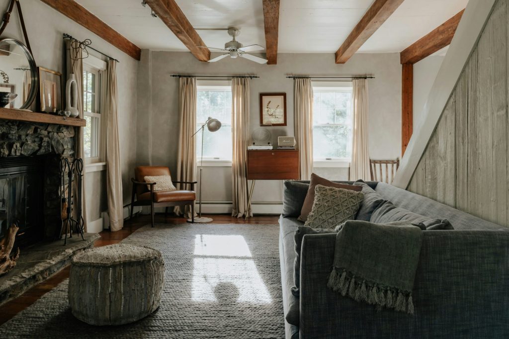 Salon rustique moderne avec poutres apparentes et cheminée en pierre, ambiance cosy.