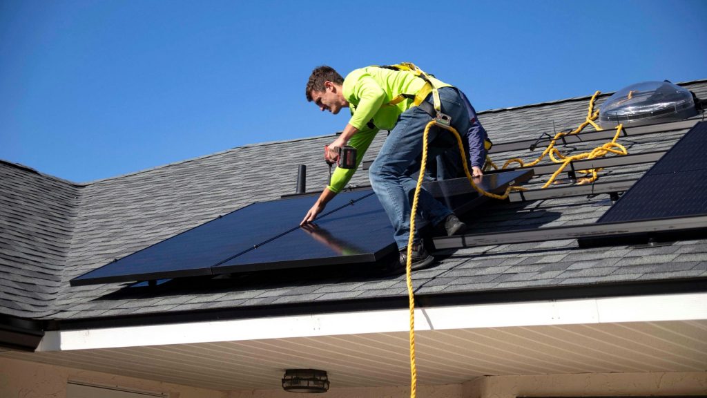 Artisan installant des panneaux photovoltaïques sur le toit d’une maison pour une production d’énergie renouvelable.